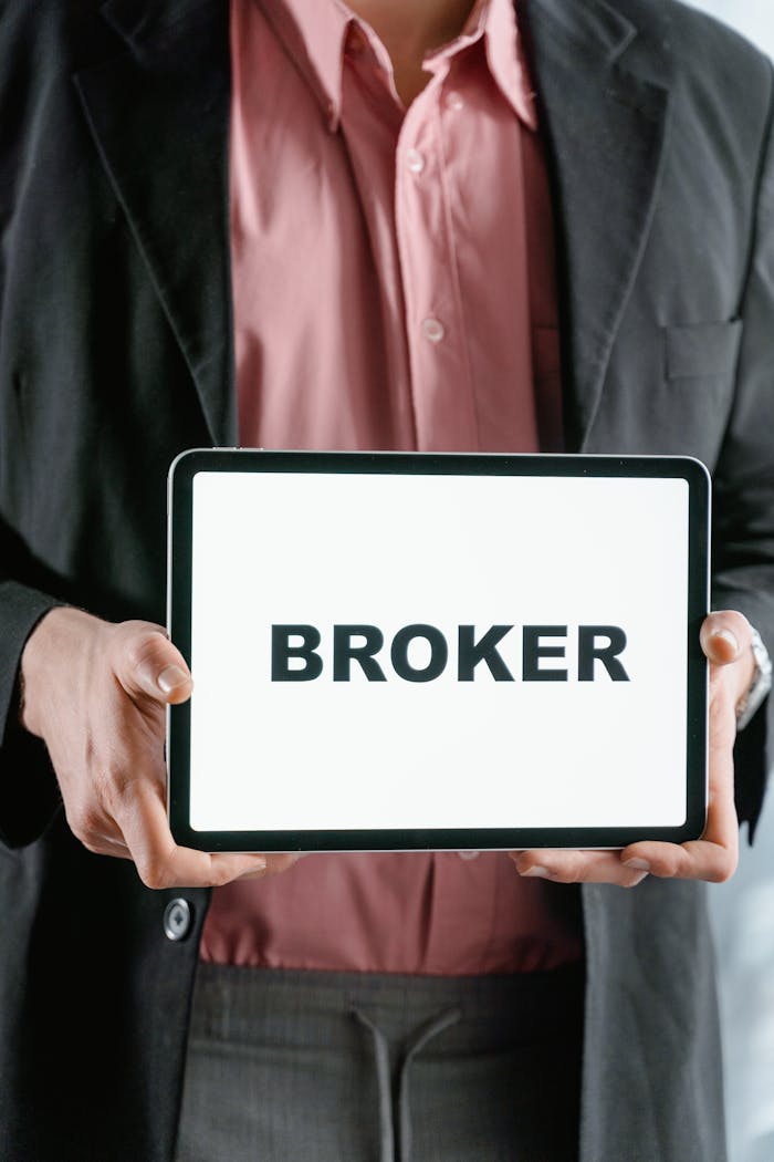 hero-img-01 Close-up of a businessman holding a tablet with 'BROKER' text, symbolizing finance and banking.